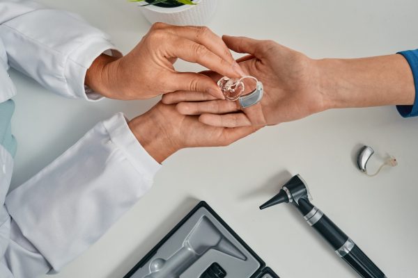 Audiologist,Puts,Modern,Bte,Hearing,Aid,In,Patient,Hand,For